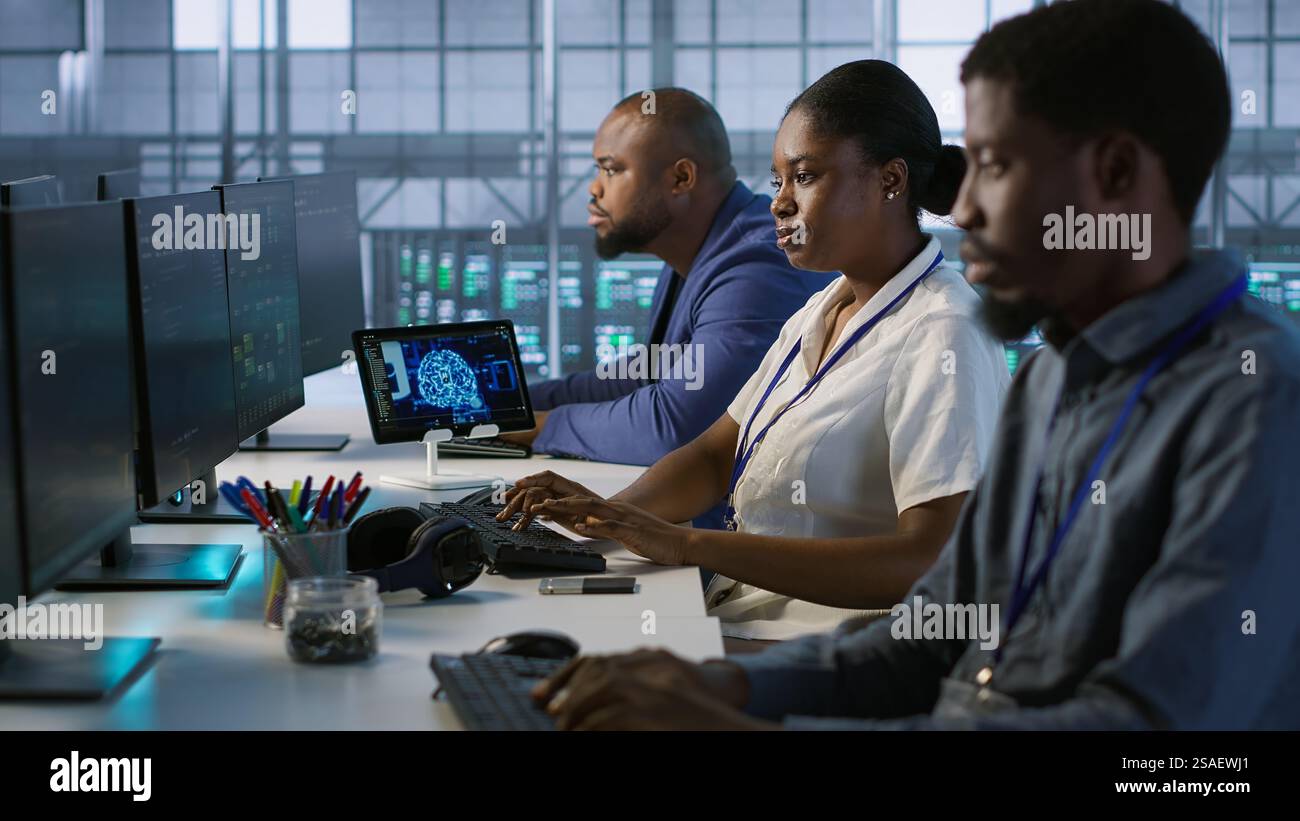 Technicians using computers and tablet in data center, implementing AI systems. Server farm experts using artificial intelligence on device to identify hardware failures impacting operations, camera A Stock Photo
