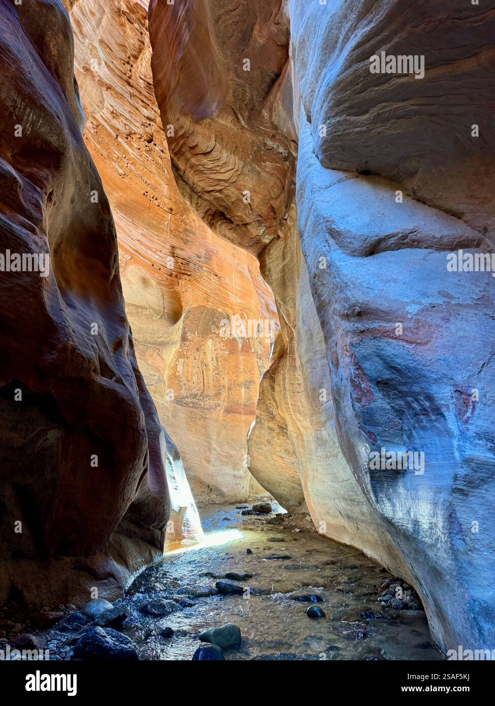 Slot canyon shot of red rock and a river with orange and blue hues from a hike at Kanara Falls in Kanaraville Utah - Smartphone Captured Stock Image