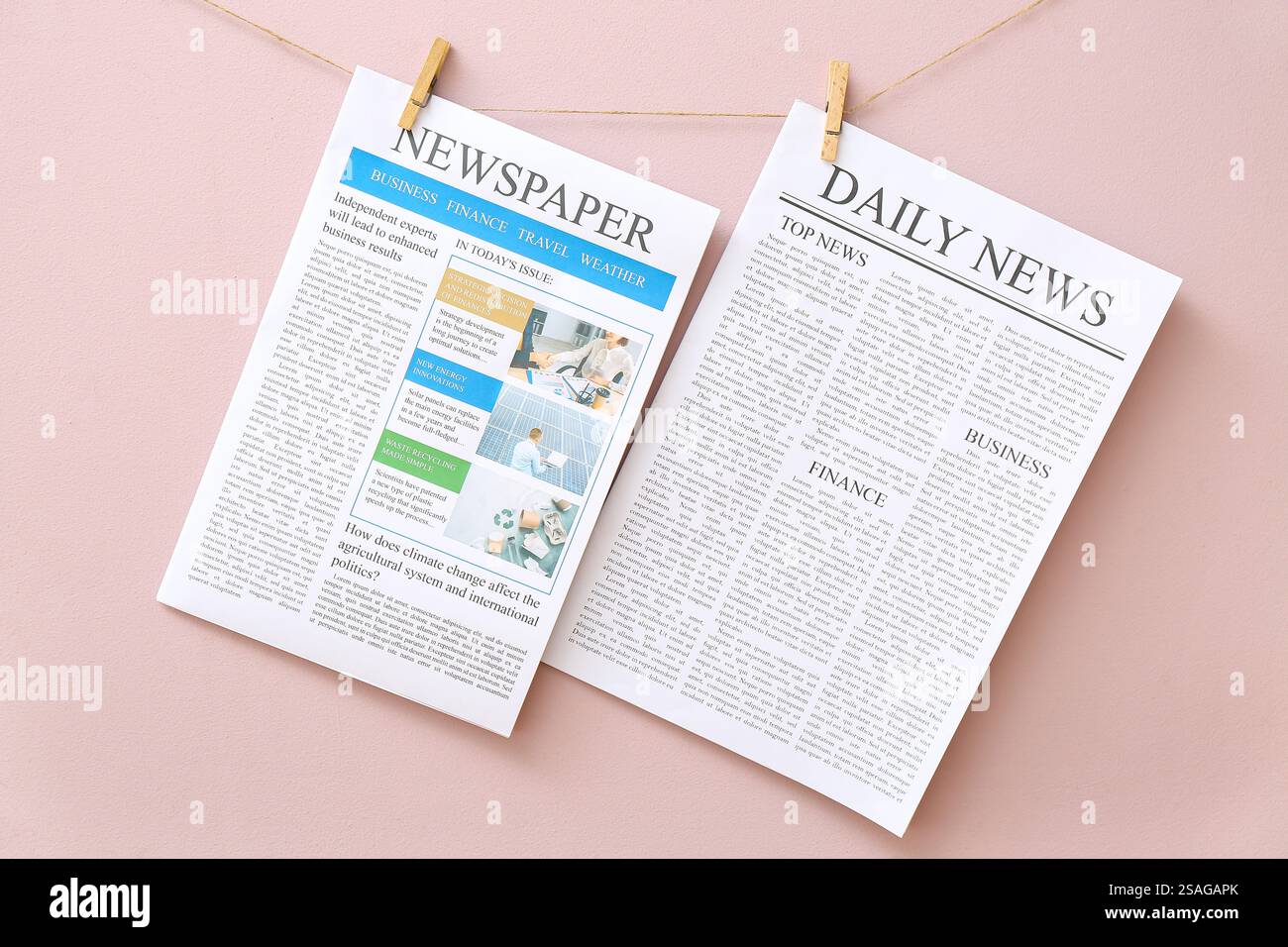 Different newspapers hanging on rope against pink background Stock Photo