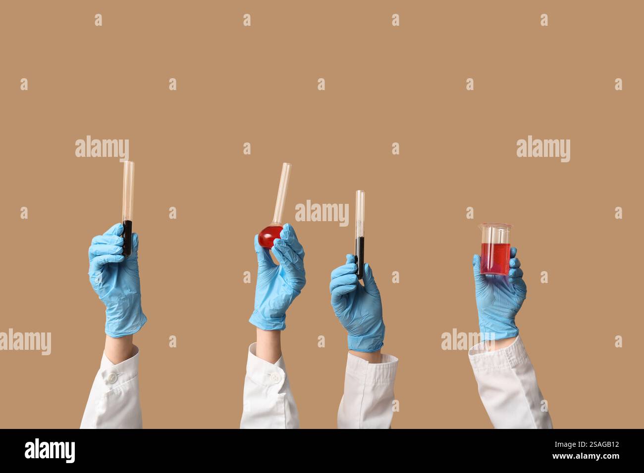 Scientist's hands holding test tubes with soil and red liquid on brown ...