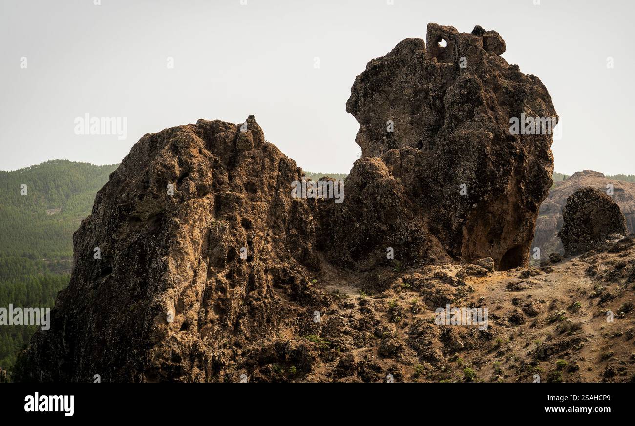 A rugged rock formation with a unique shape, surrounded by green hills ...