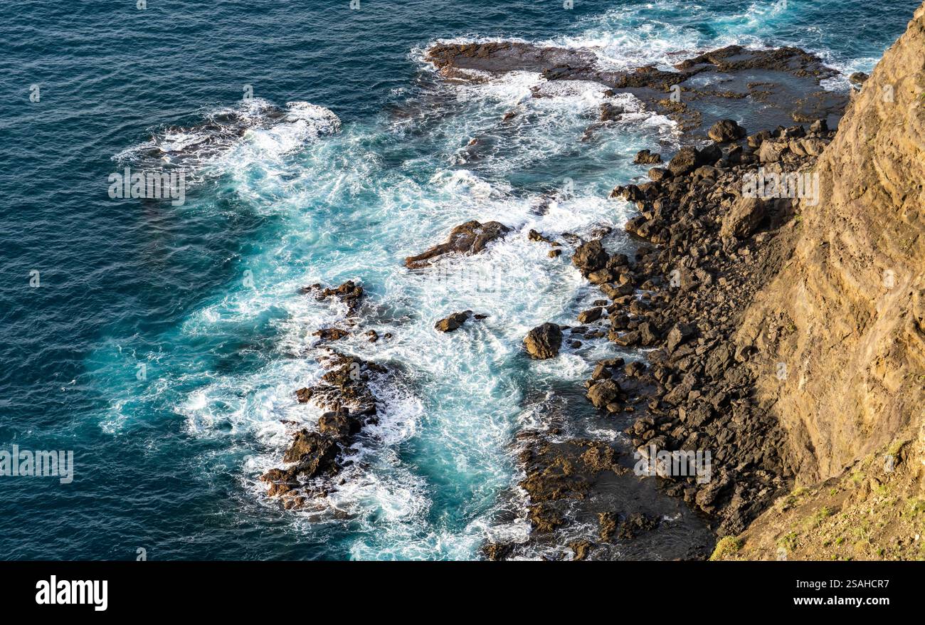 Aerial view of rocky coastline with waves crashing against the shore ...