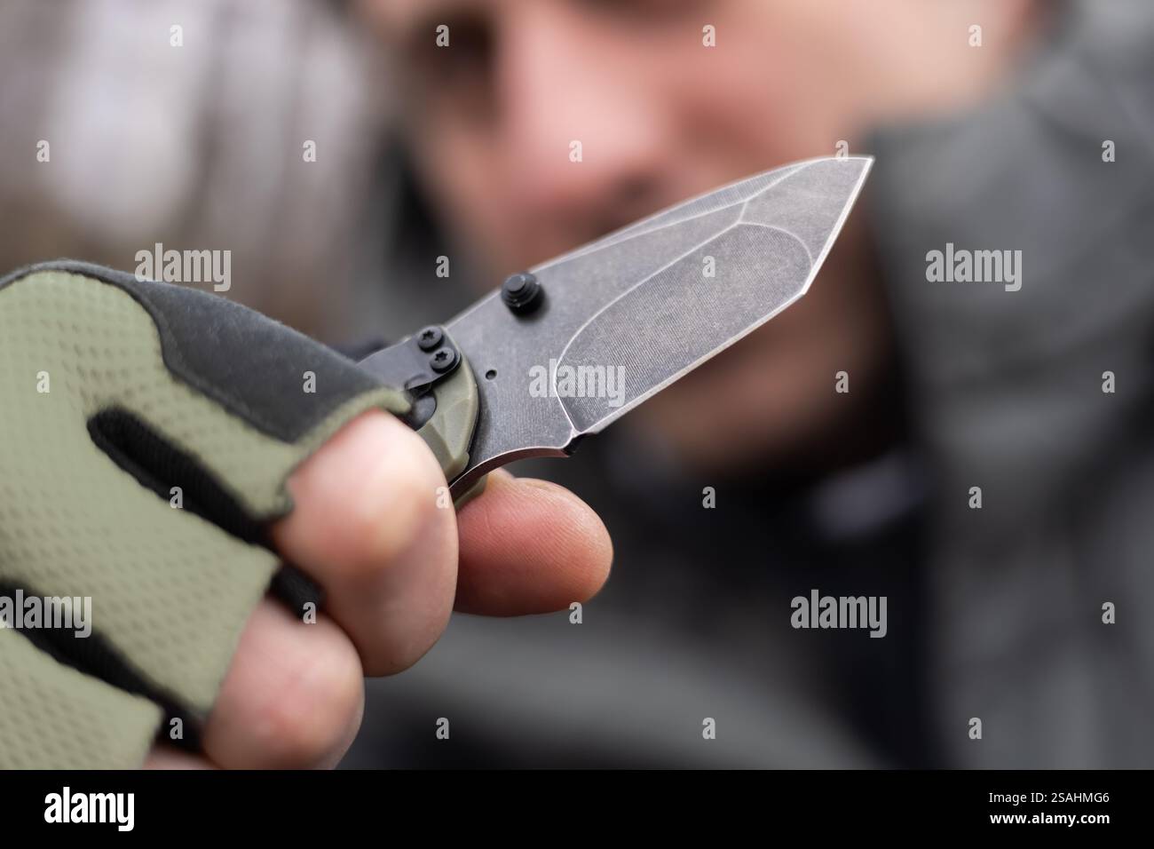 The man wearing tactical gloves using folding knife. Stock Photo