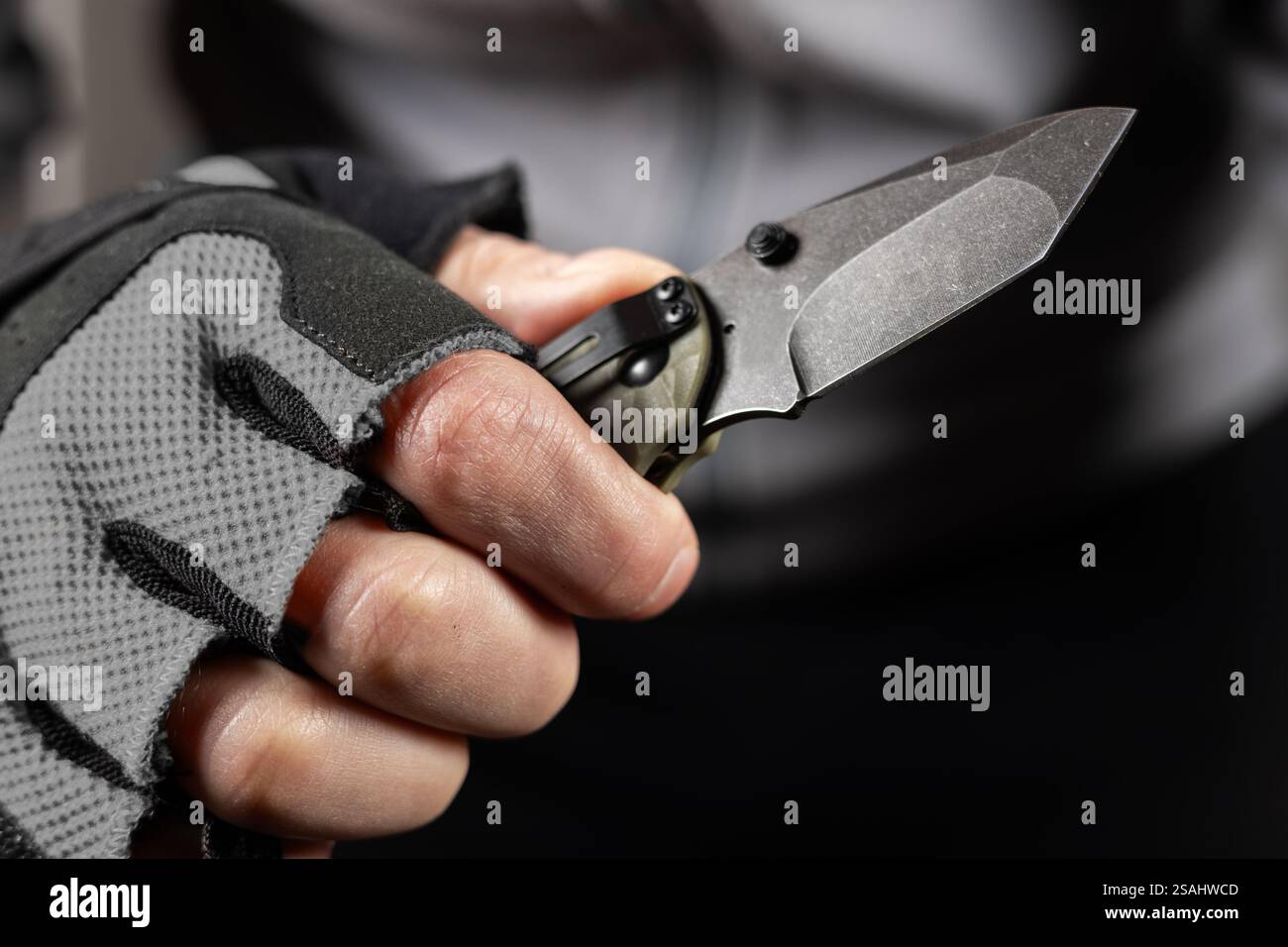 The man wearing tactical gloves using folding knife. Stock Photo