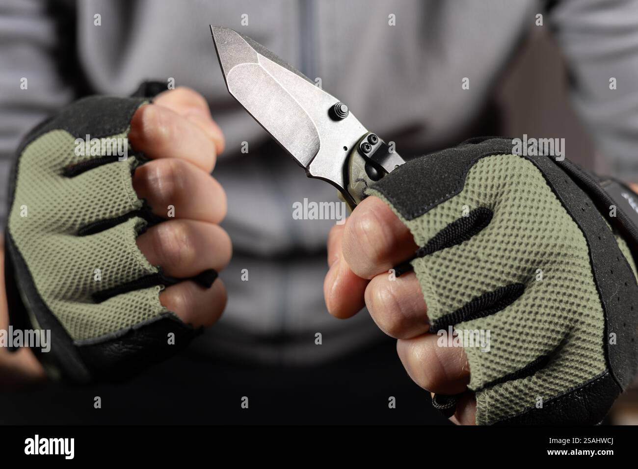 The man wearing tactical gloves using folding knife. Stock Photo