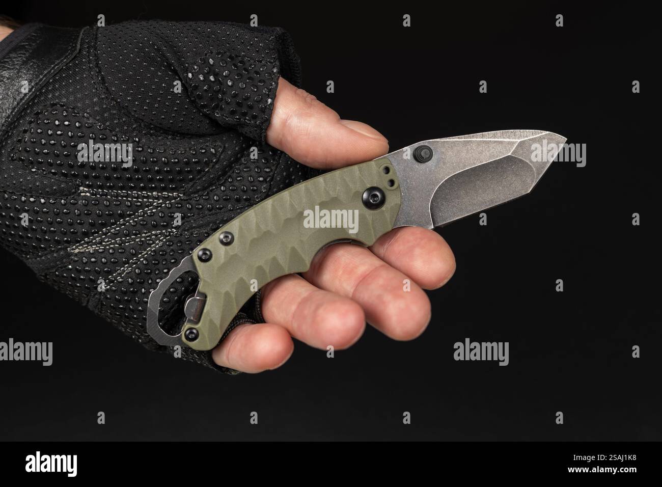The man wearing tactical gloves using folding knife. Stock Photo