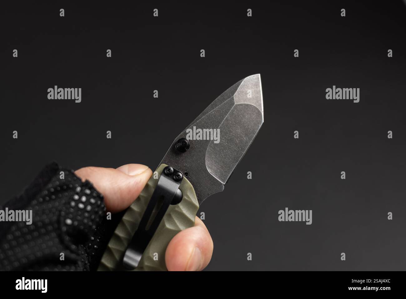 The man wearing tactical gloves using folding knife. Stock Photo