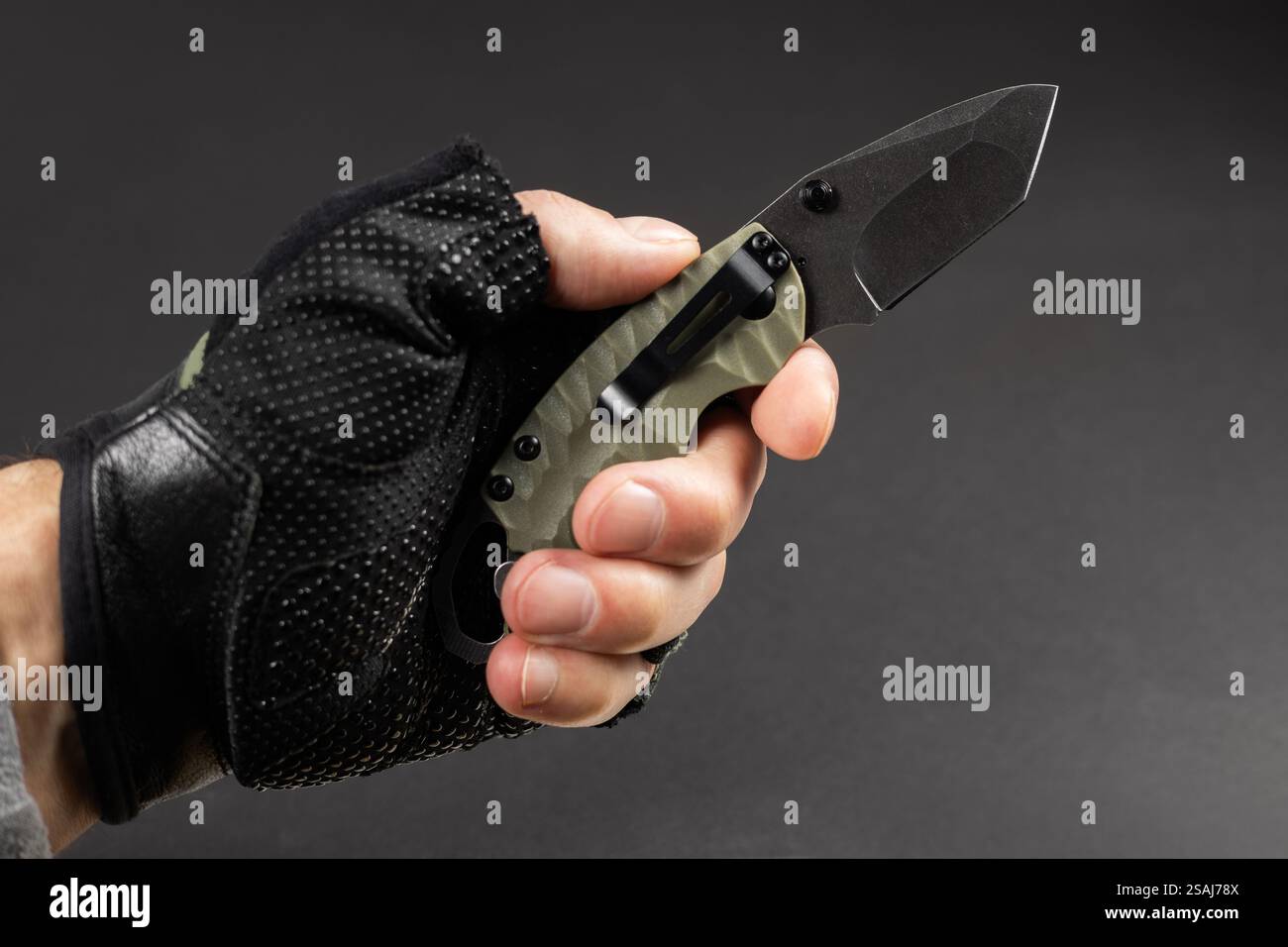 The man wearing tactical gloves using folding knife. Stock Photo