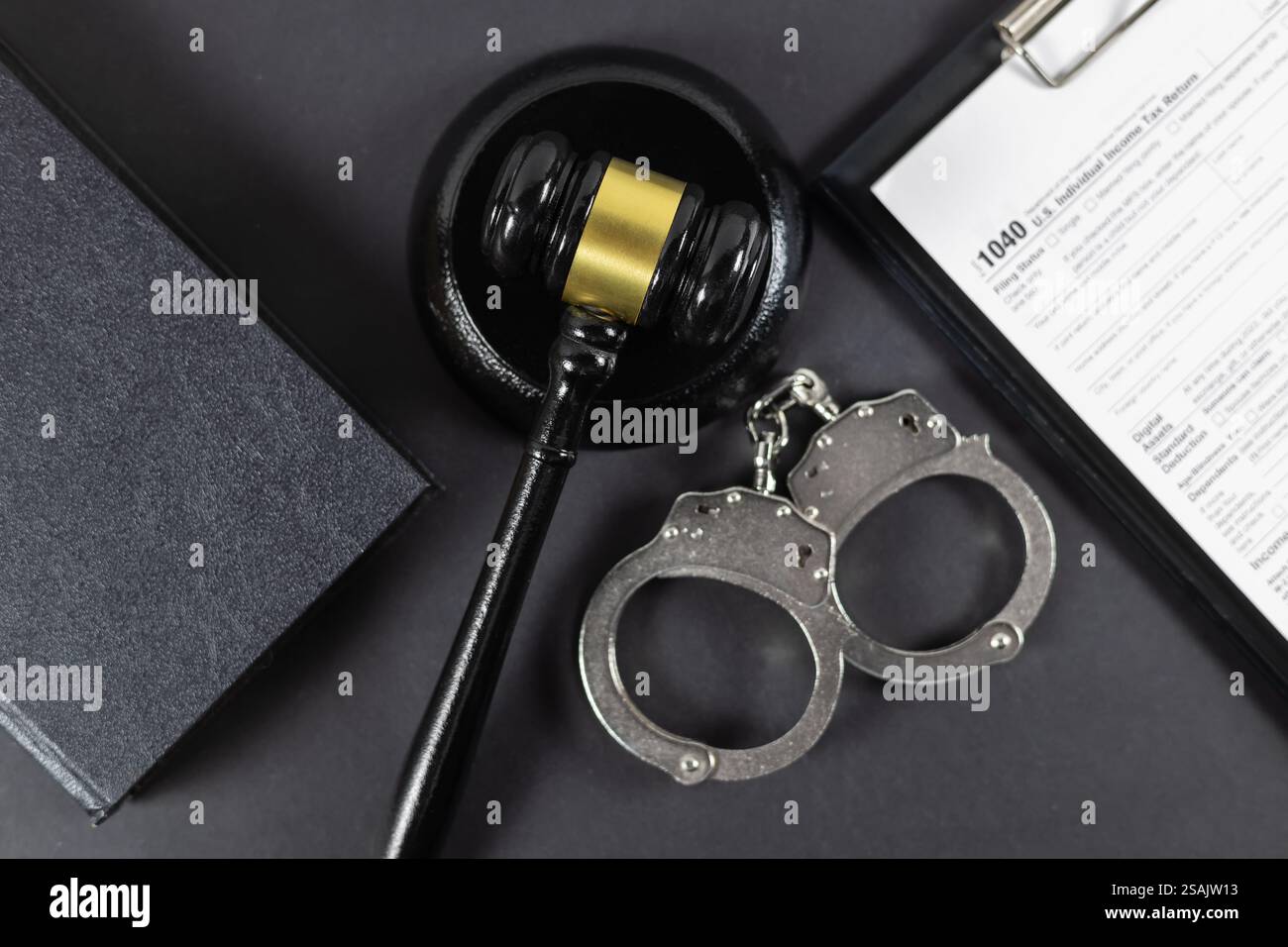 Judge's gavel and law book with handcuff lying on tax form. Time for tax, illegal concept. Stock Photo