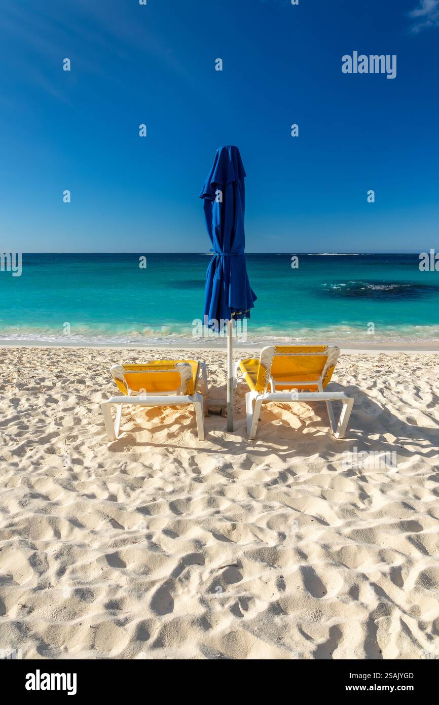 Two yellow beach chairs and blue parasol in Shoal Bay beach, Caribbean ...