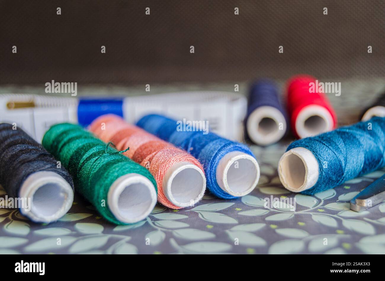 Reels of different coloured thread on a green floral background Stock ...