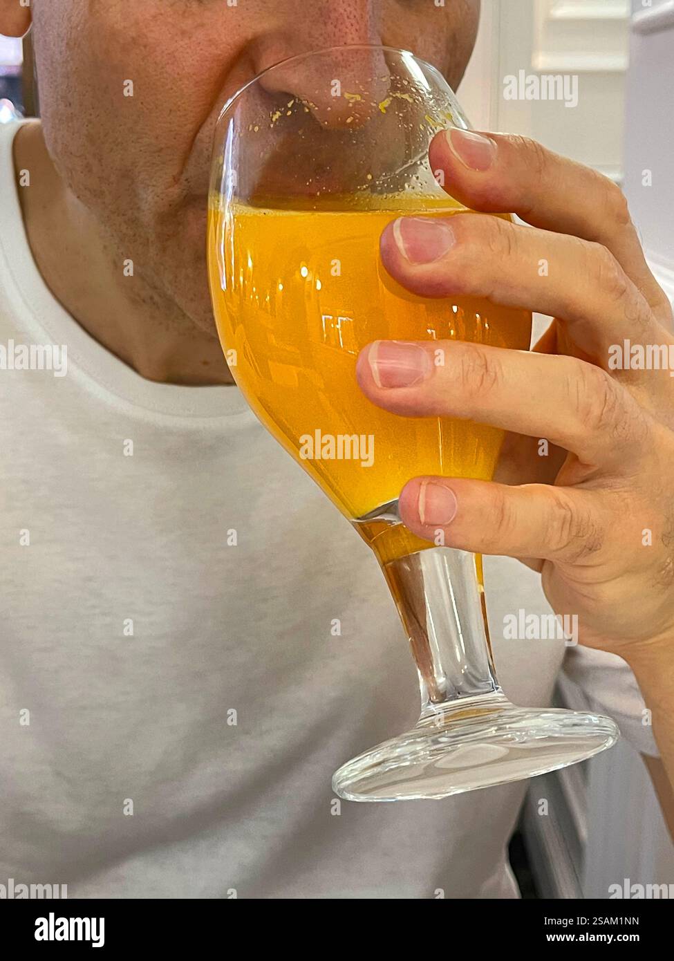 Man drinking a glass of orange juice. - Smartphone Captured Stock Image