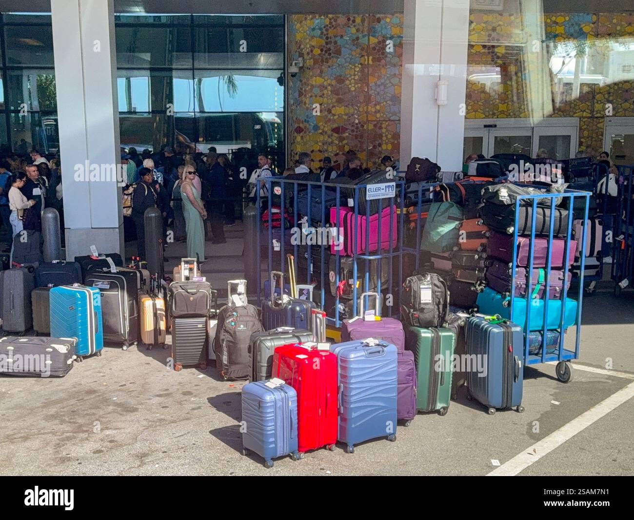 Miami, Florida, USA - 4 January 2024: Luggage stacked on trolleys for loading onto a cruise ship. In the background are poassengers waiting to embark. - Smartphone Captured Stock Image