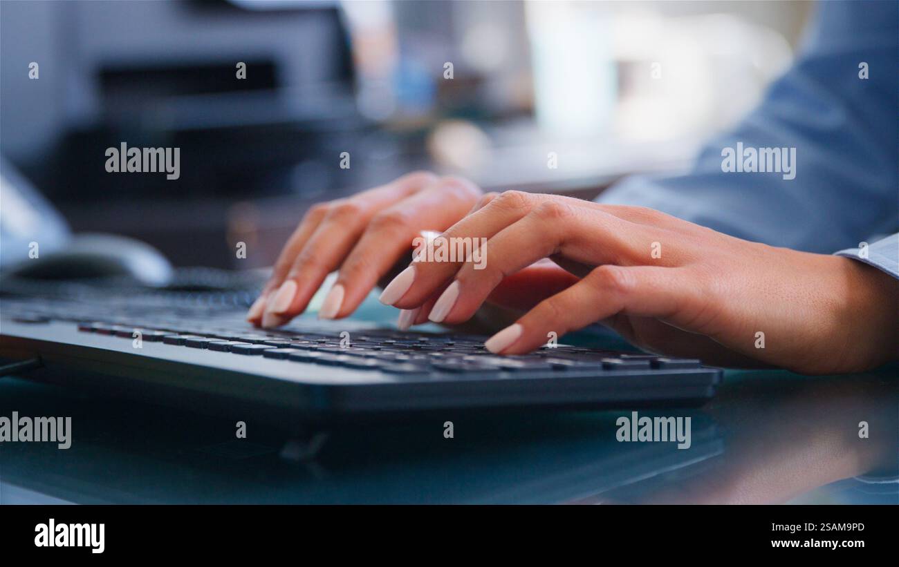 Close Up On Hands Of Businesswoman Sitting At Desk In Office Typing On Computer Keyboard Stock Photo
