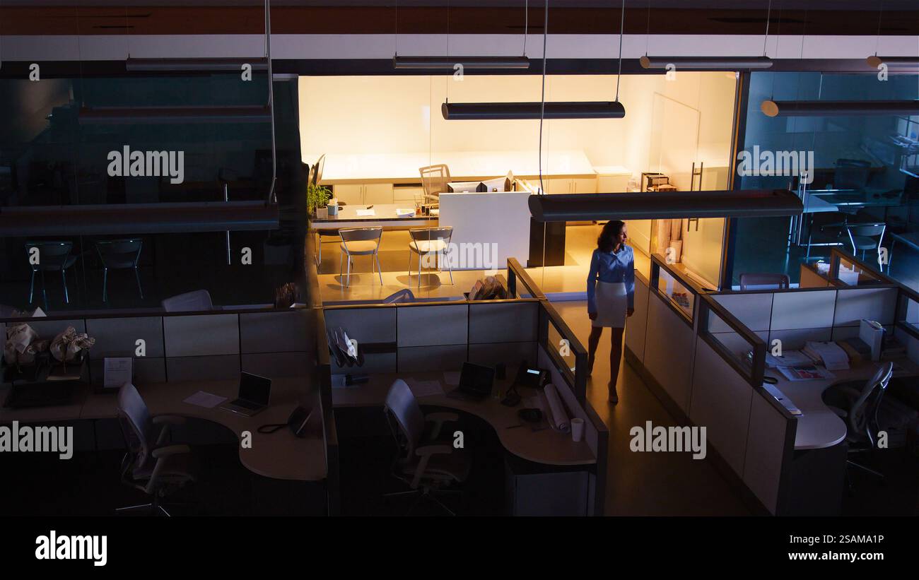 Wide Angle Shot Of Businesswoman Working Late At Night Standing In Empty Office Stock Photo