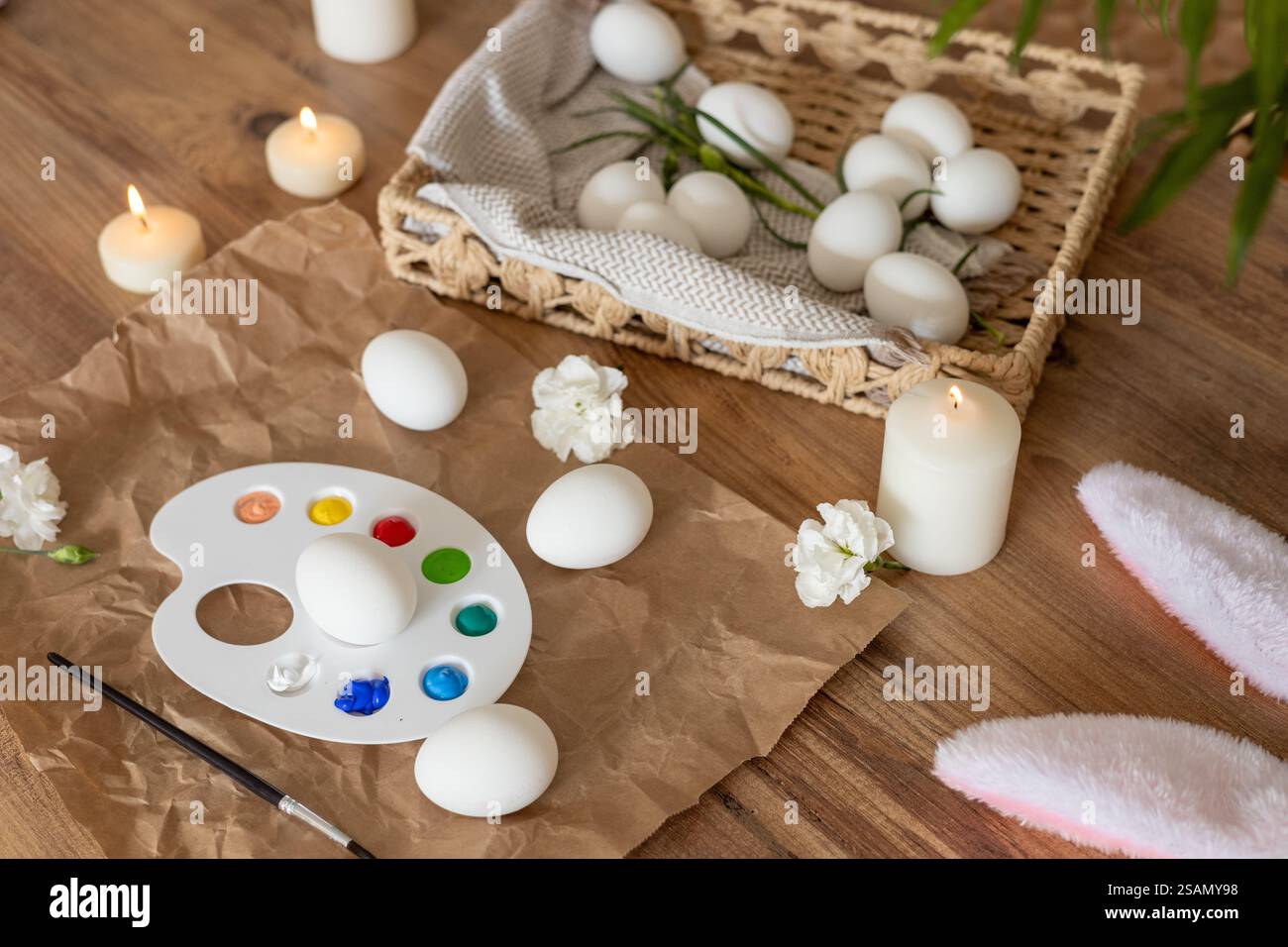Creative Easter egg decorating activity with candles and flowers in spring setting Stock Photo