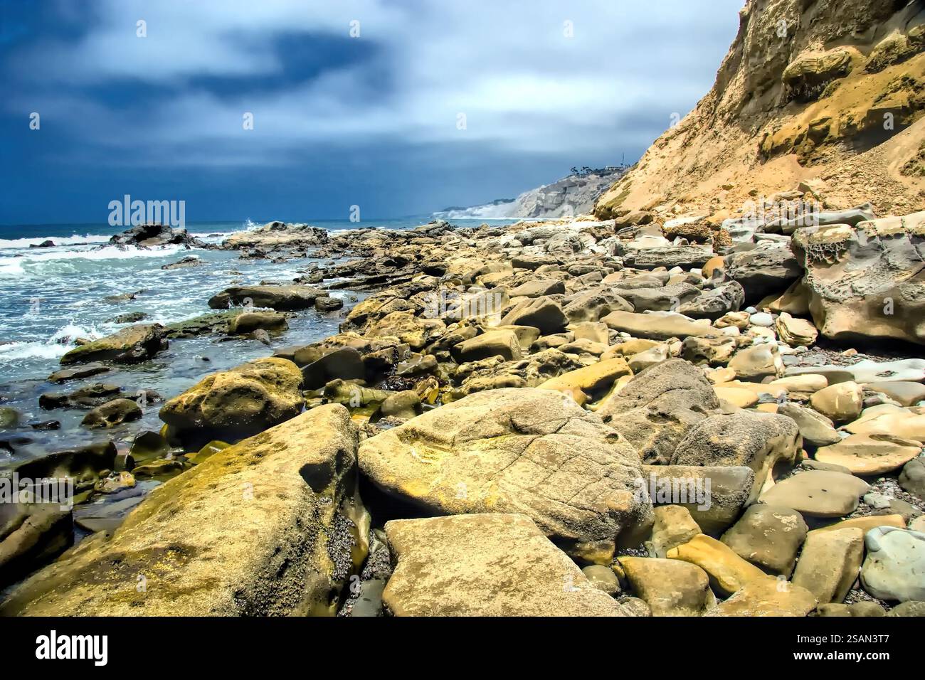 A rocky shoreline with a large body of water. The water is choppy and ...
