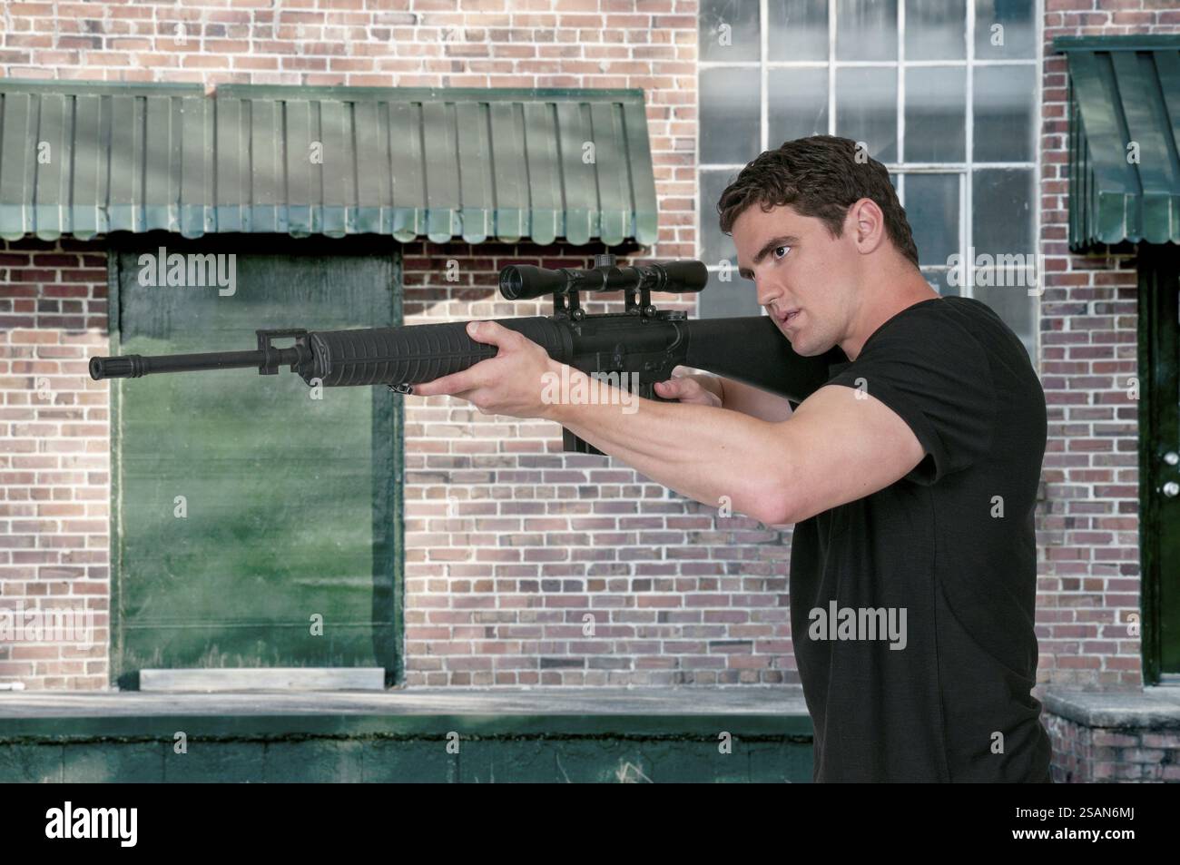 Handsome man holding an automatic assault rifle Stock Photo - Alamy