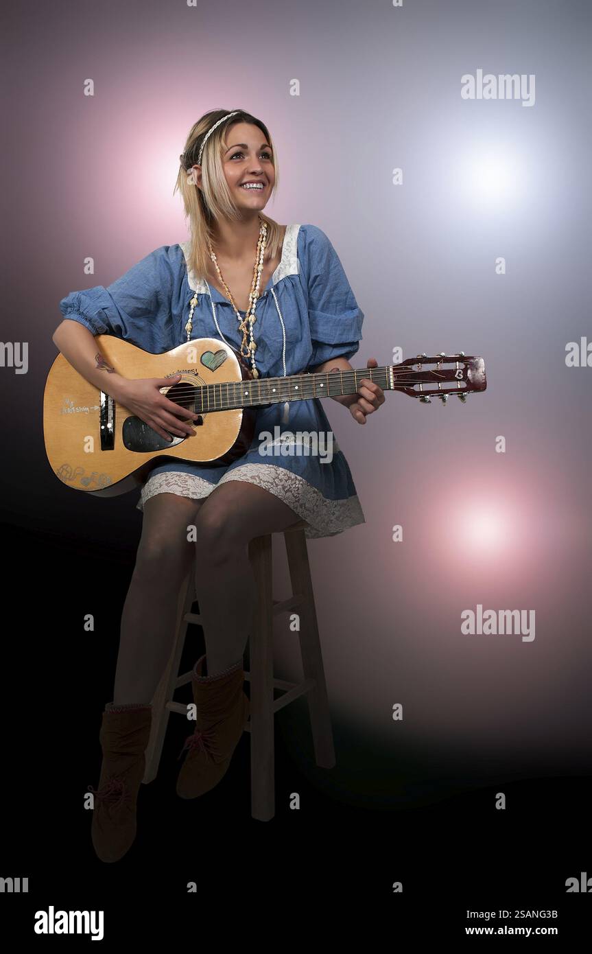 Beautiful young woman playing an acoustic guitar Stock Photo - Alamy