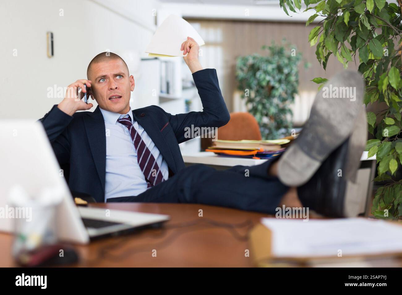 Irritated businessman having difficult phone talk Stock Photo