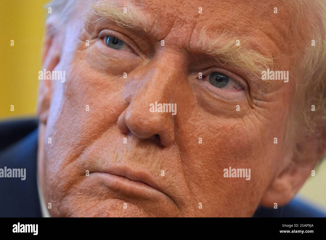 President Donald Trump listens to a question as he signs executive