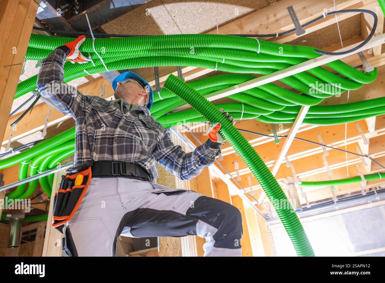 A worker in protective gear is attaching bright green air duct tubing ...