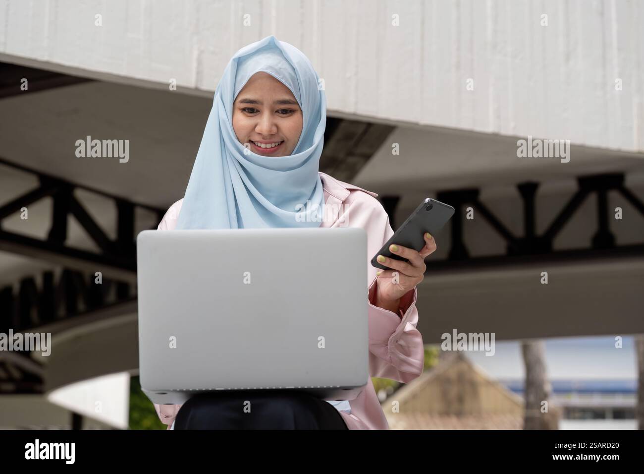 Muslim woman in hijab working on laptop and smartphone for business ...