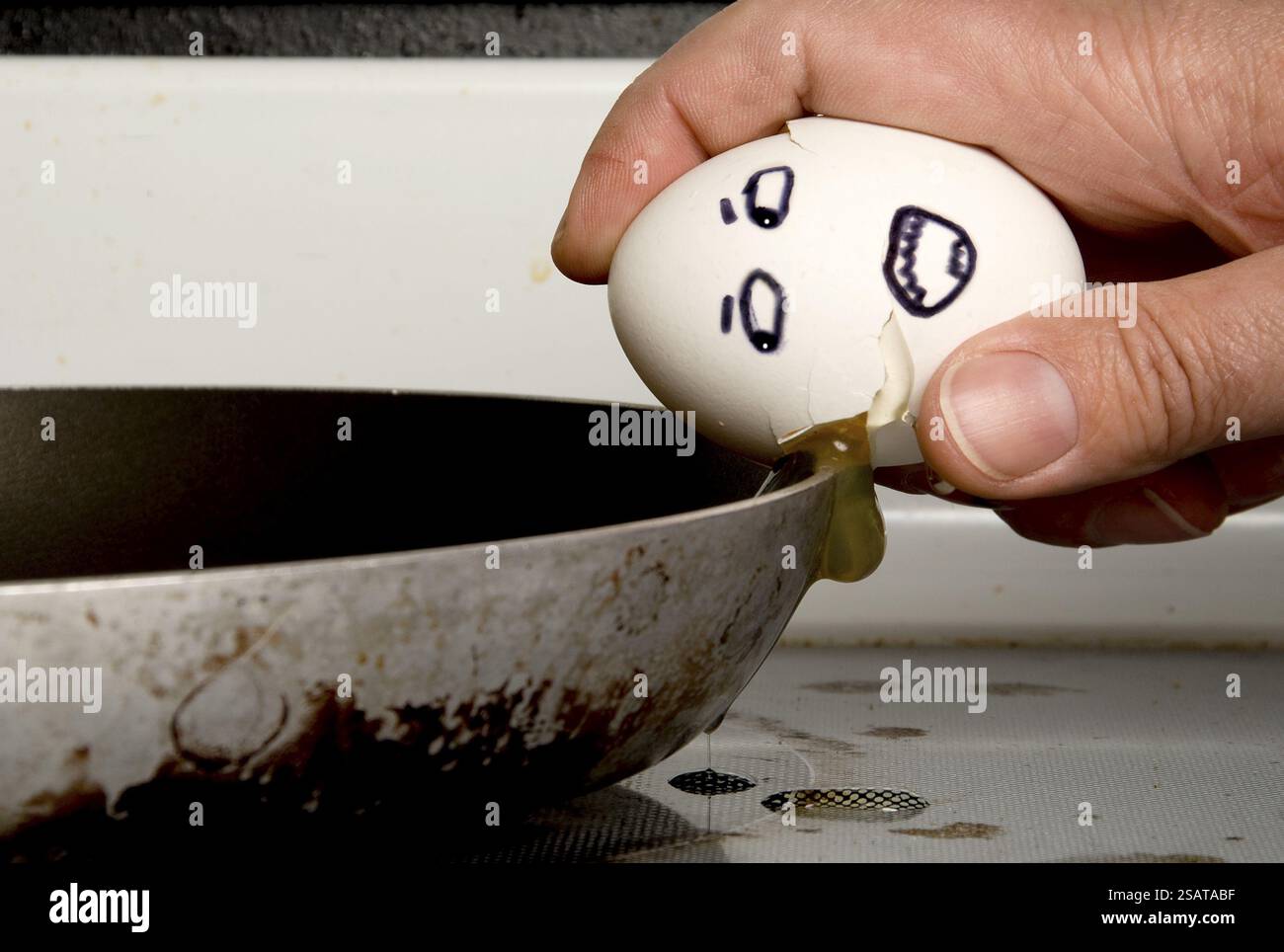 An egg being cracked on a frying pan Stock Photo