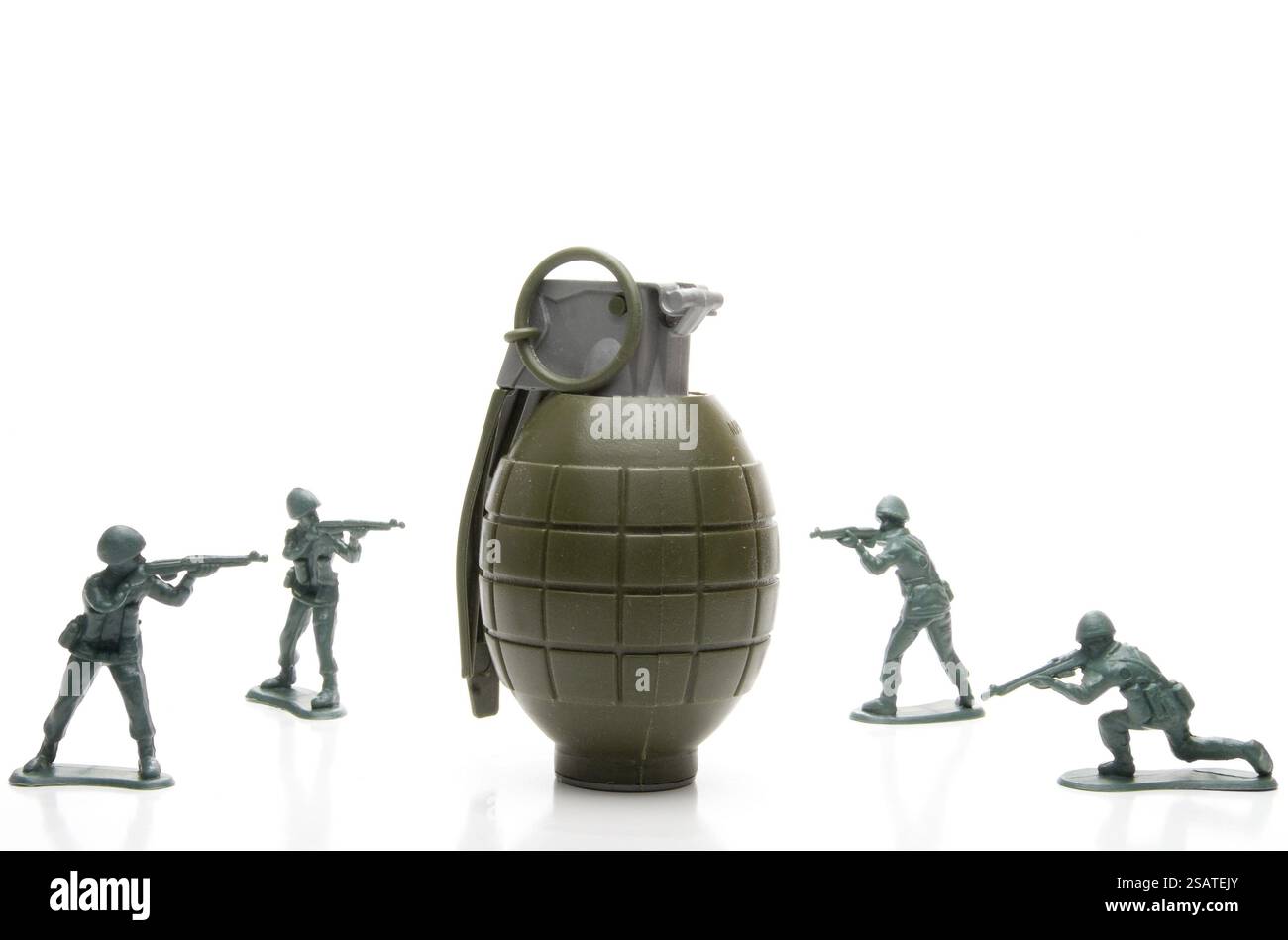 Several toy soldiers surrounding a hand grenade Stock Photo