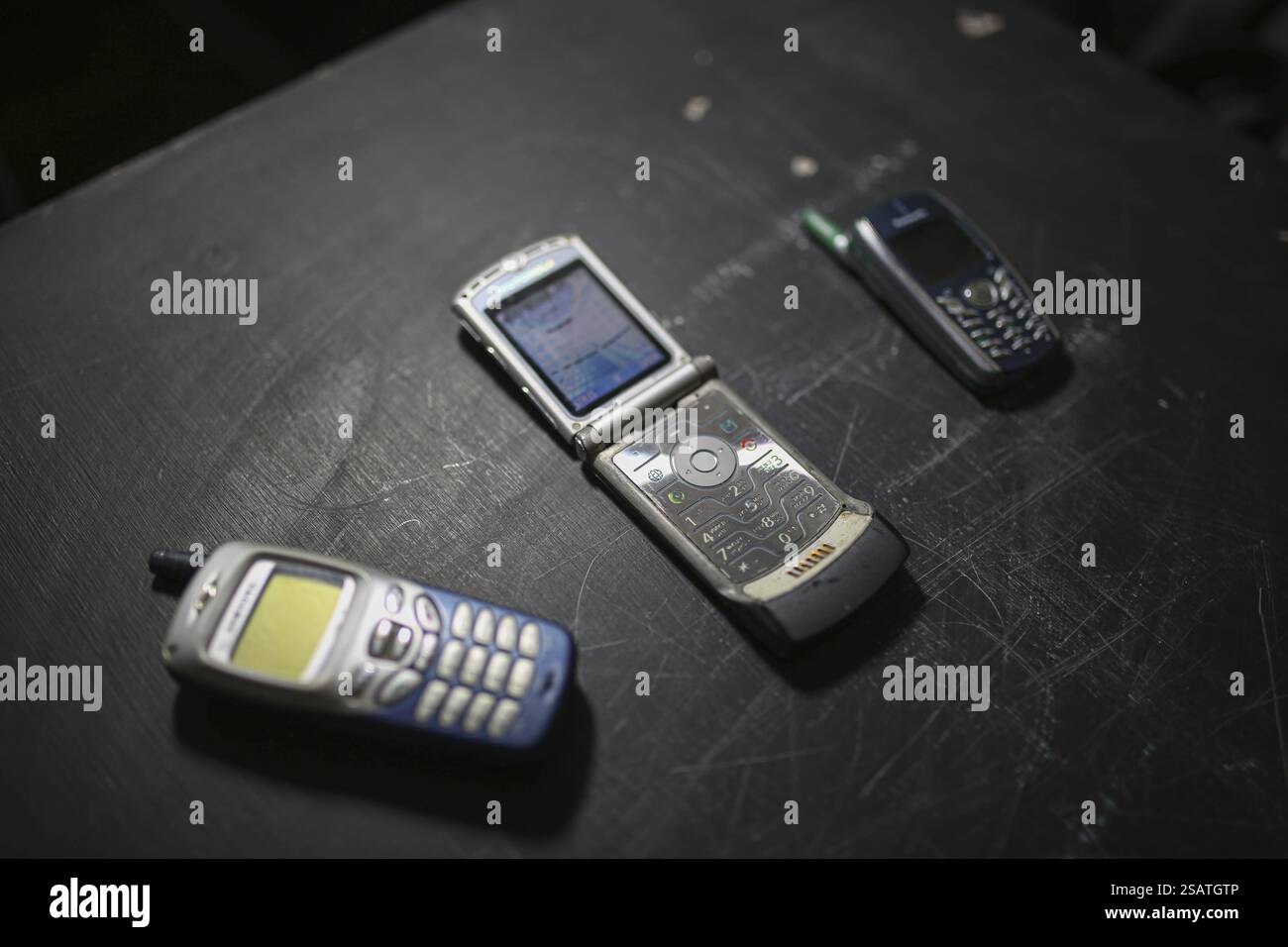 Three vintage mobile phones placed on a dark surface Stock Photo