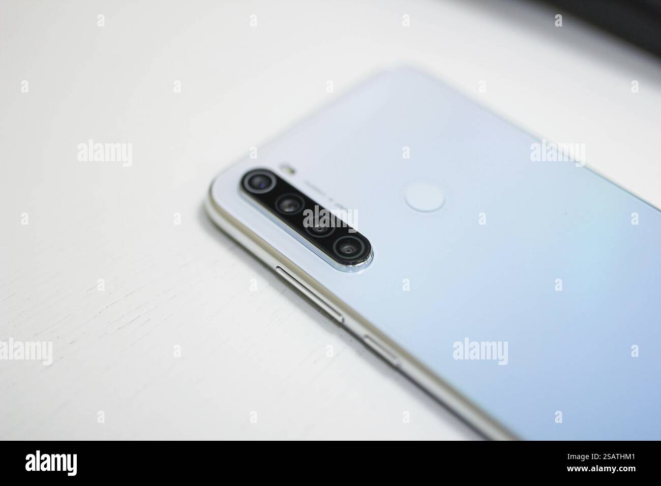 Close-up of a silver smartphone with quad cameras on a white surface Stock Photo
