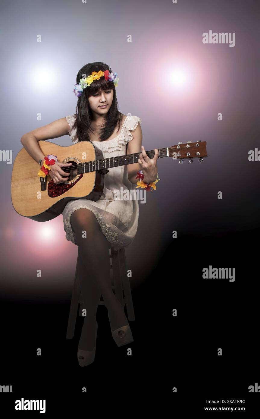 Beautiful young woman playing an acoustic guitar Stock Photo - Alamy