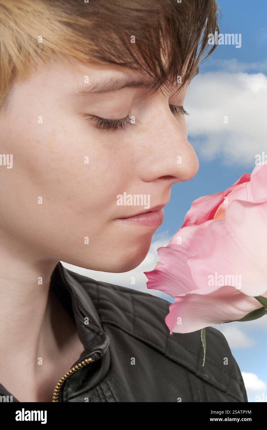 Beautiful woman smelling a fresh cut rose Stock Photo - Alamy