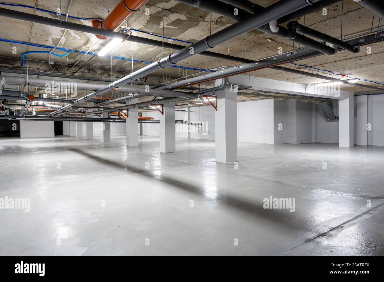 View of Empty underground parking lot with industrial features and bright ...