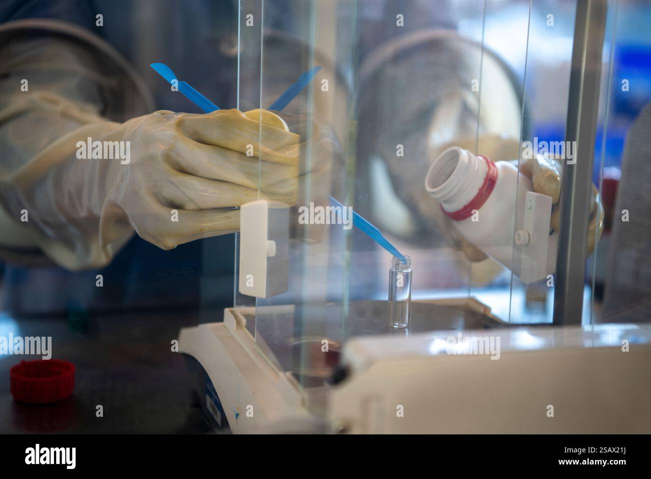 gloved hand biotech lab blue scoop place substance in small vial Stock ...