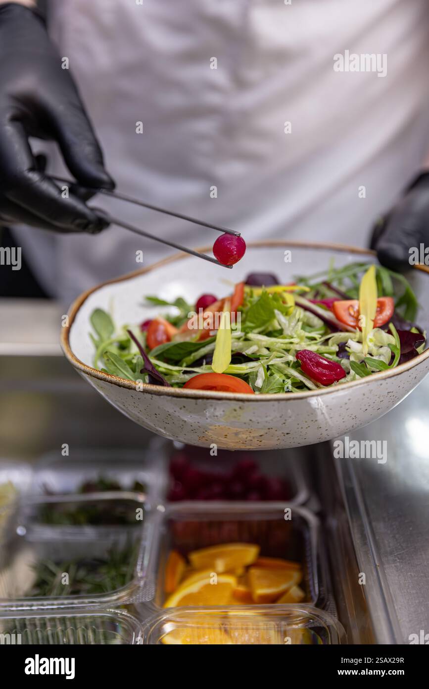 Chef adding final touches to fresh colorful salad in restaurant kitchen Stock Photo