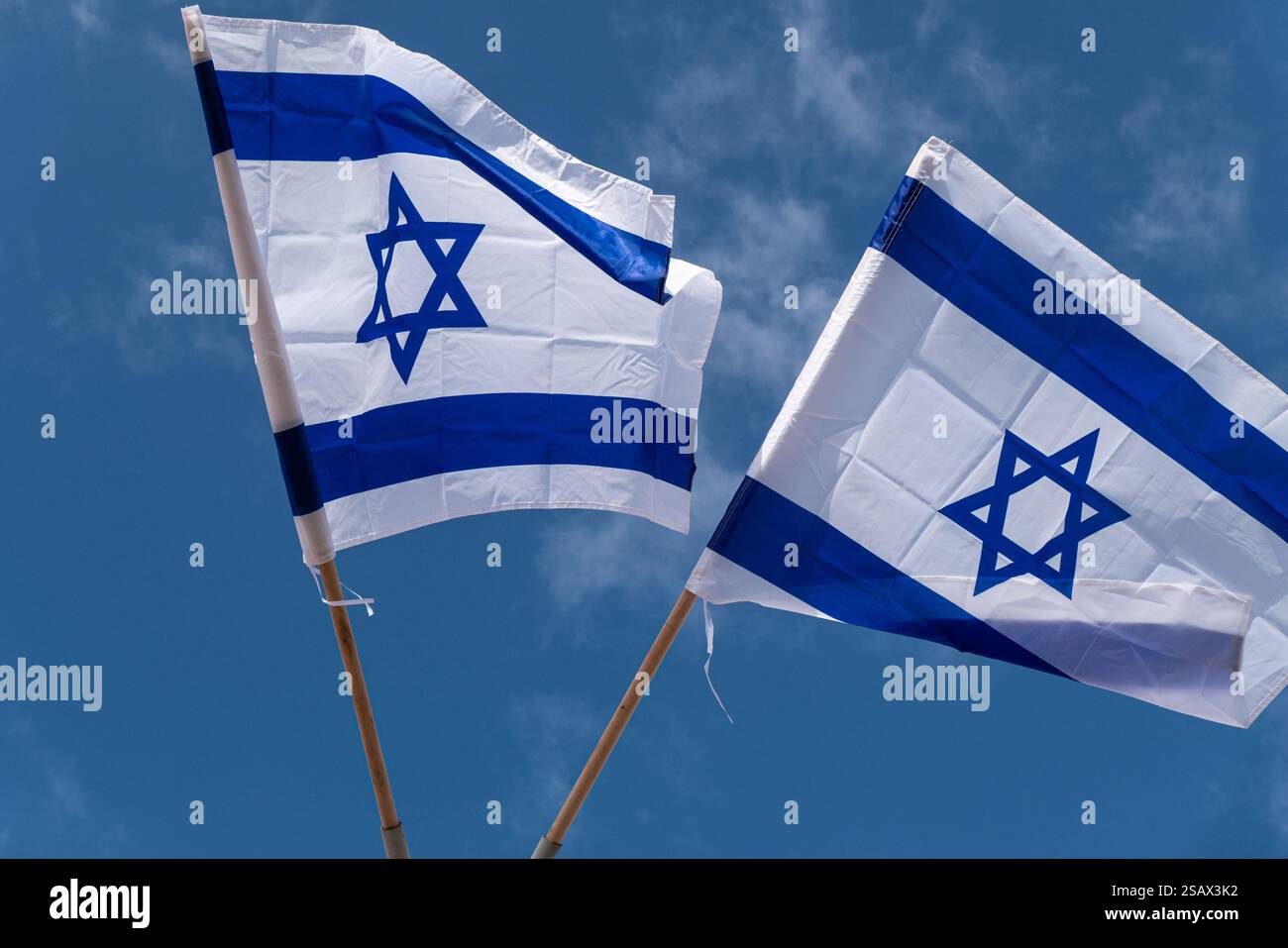 Two Israeli flags waving proudly in the wind against a vibrant blue sky ...