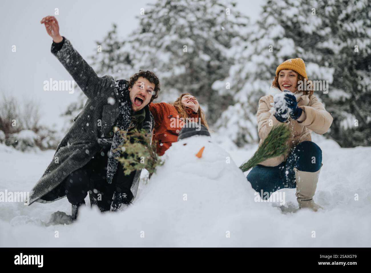Cheerful friends building a snowman together in a snowy forest with ...