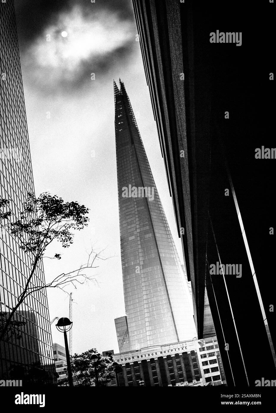 Dramatic black and white image of The Shard in London, rising into a moody, overcast sky. High-contrast atmospheric architectural photograph Stock Photo