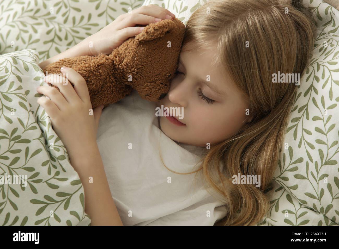Sweet little girl sleeping in the bed and hugging her teddy bear Stock ...