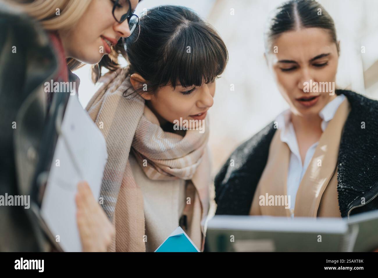 Three professional women collaborating outdoors and discussing documents Stock Photo
