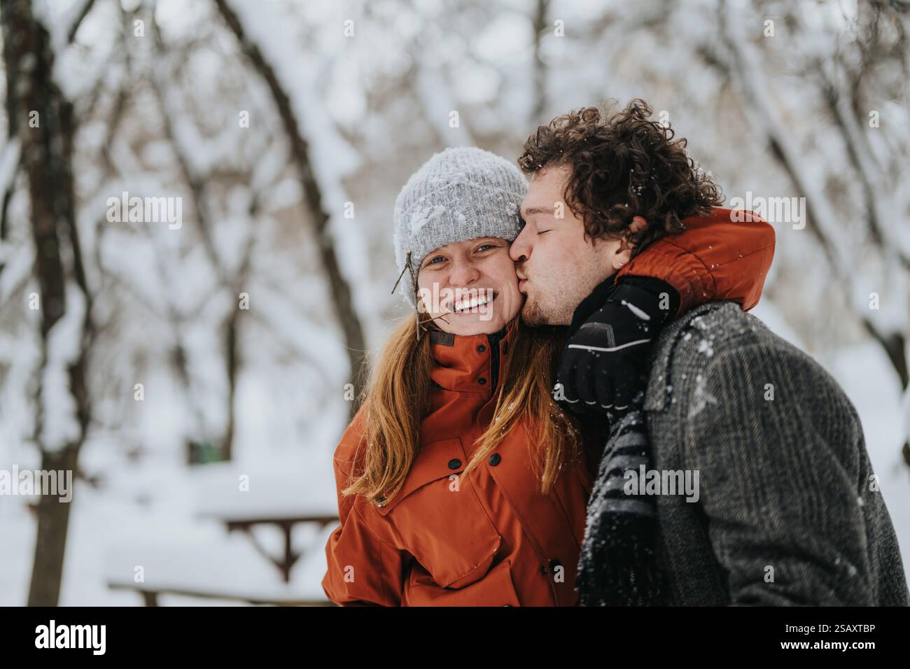 Couple sharing a snowy outdoor moment and enjoying the winter weather ...