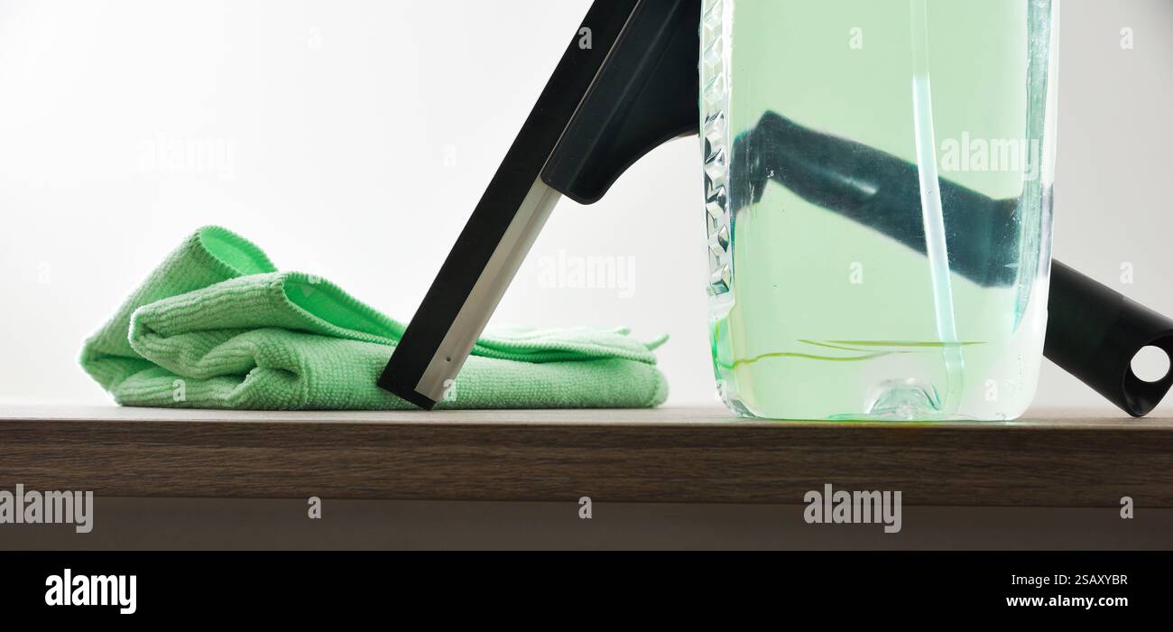 Window cleaner spatula, spray product and microfibre cloth on wooden table white isolated background. Front view. Stock Photo