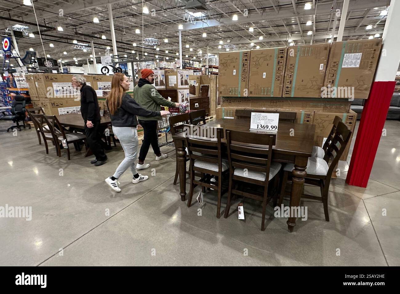 Shoppers pass by a dining room set on display in a Costco warehouse ...