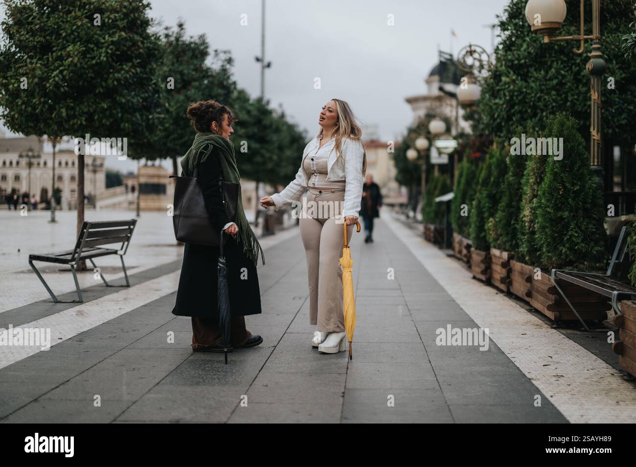 Two women talking with umbrellas on a pedestrian urban walkway Stock ...