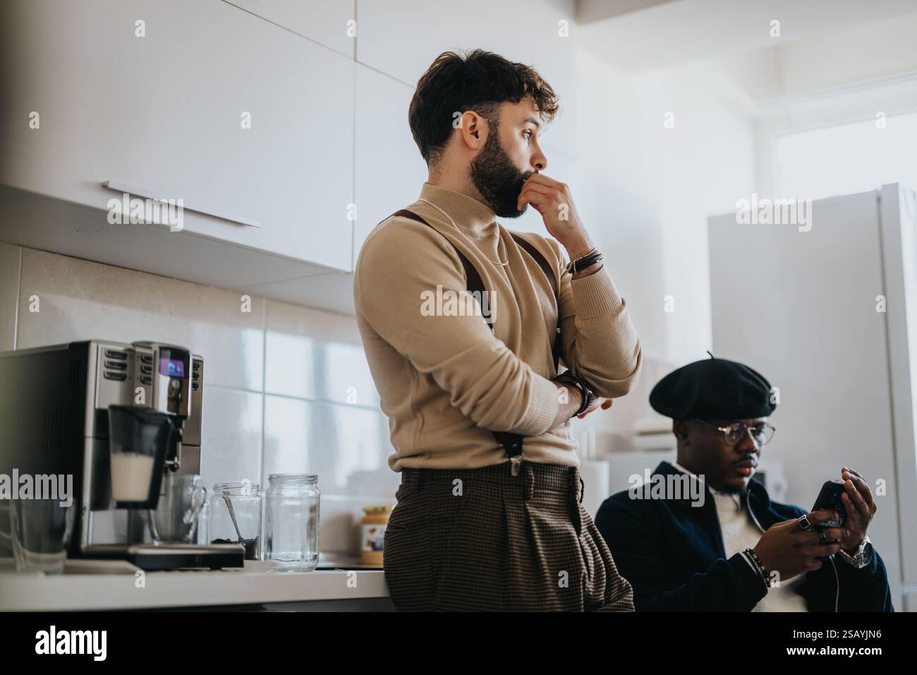 Two young professionals in a modern office kitchen discussing and using technology Stock Photo