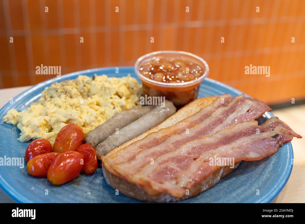 Western breakfast with bacon, bread, tomatoes, chicken sausages, baked ...