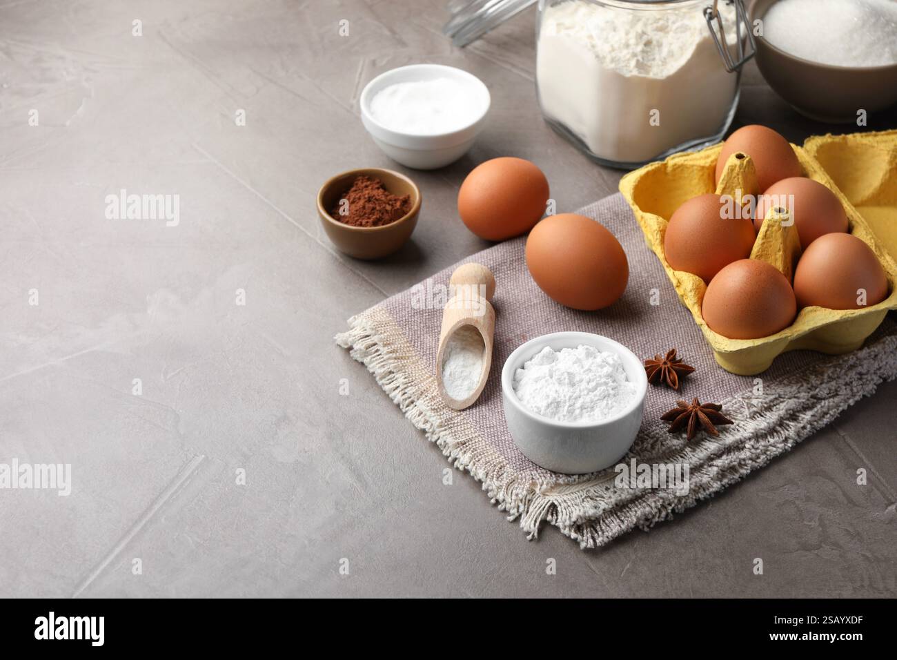 Baking powder and other products on grey textured table. Space for text ...