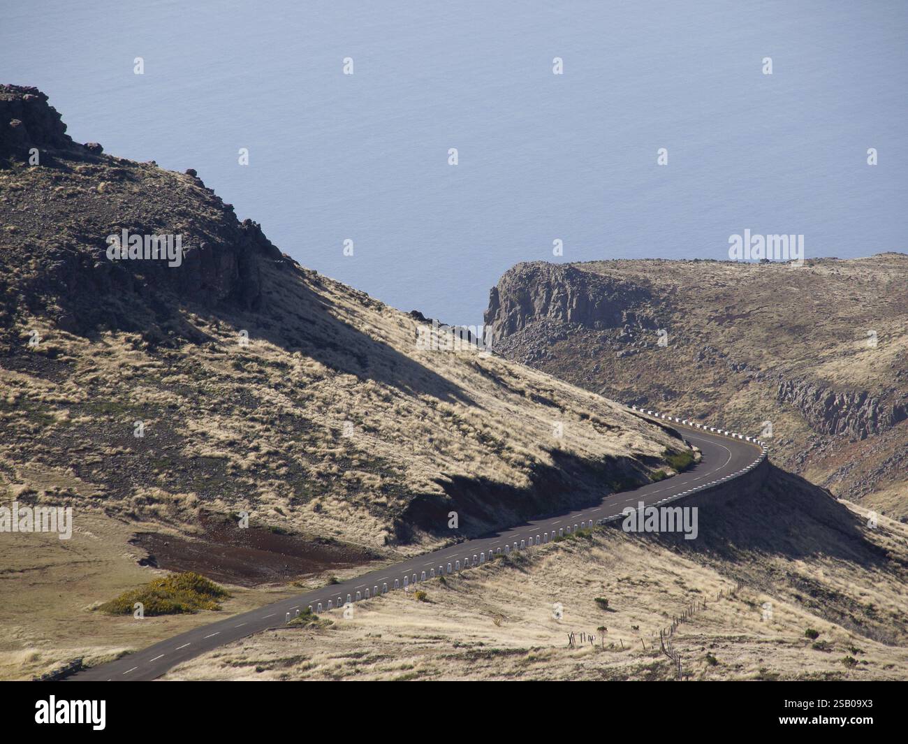 A winding road meanders through a barren, mountainous coastal landscape ...