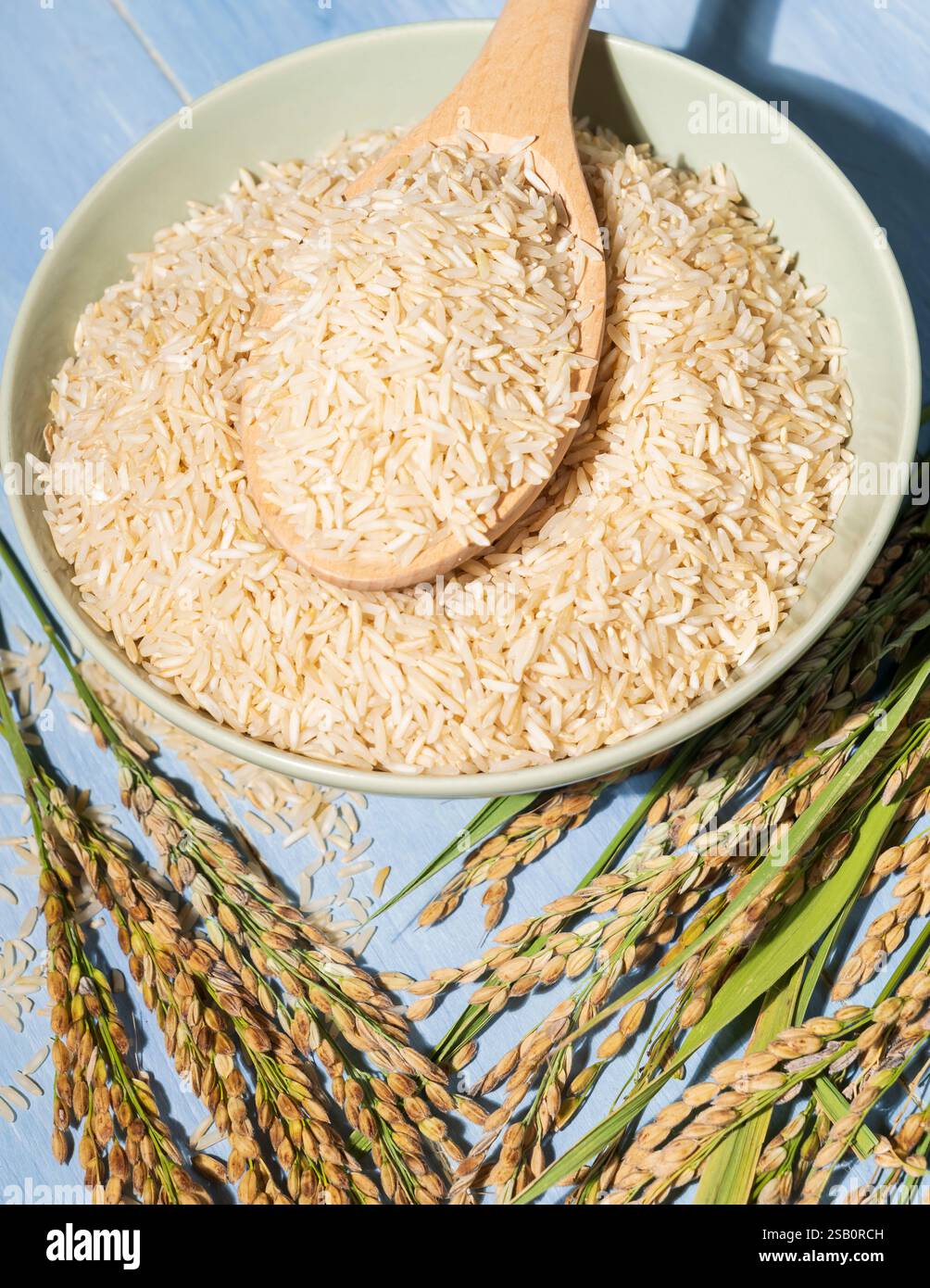 A bowl of brown-rice is placed on a table next to a spoonful and ears ...